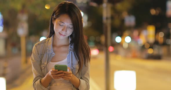 Woman using cellphone at night in Hong Kong 