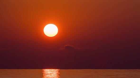 Timelapse of Sunset of the Great Red Sun in the Sea. Orange Sunny Path with Sea Reflections.