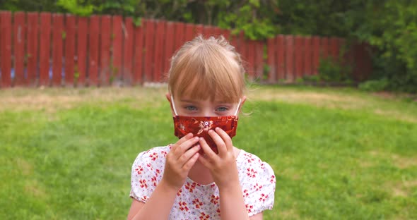 Little girl adjusting her protective face mask.