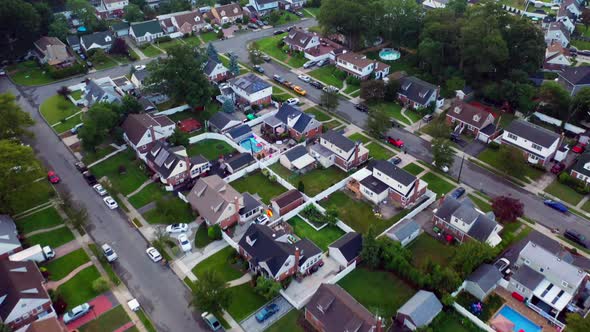 A top down view over a suburban neighborhood in the evening. The camera is looking down as the drone