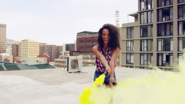 Fashionable young woman on urban rooftop using a smoke grenade