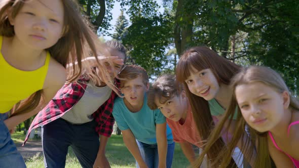 Multiethnic Kids Bending and Looking at Camera Outdoors in Park