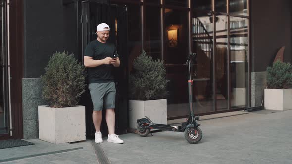 Tourist Man on Electric Scooter with Phone in Hand