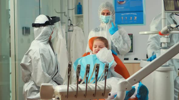 Child in Protection Suit Showing Dental Problem to Orthodontist