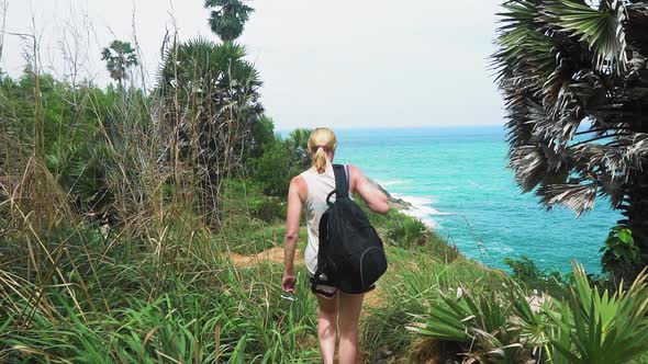 tourist girl is walking along the trail in the rainforest. seashore with palm trees