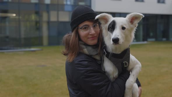 Woman Standing at Park and Holding Her White Dog