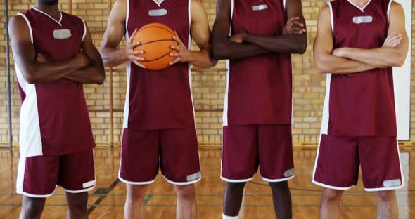 Confident basketball players holding basketball in court