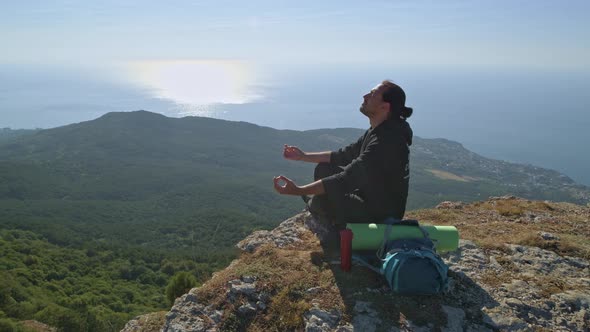 A young tourist is enjoying the sea view from a high mountain.