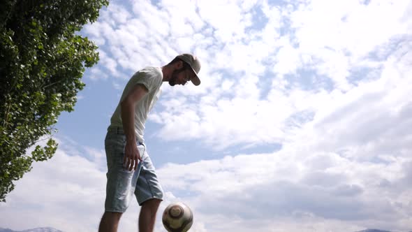 Caucasian man showing his football juggle skills in a park, dutch angle.
