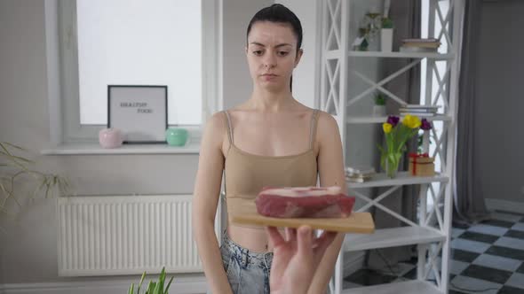 Confident Slim Beautiful Woman Crossing Hands No Gesture Looking at Camera with Raw Beef at Front