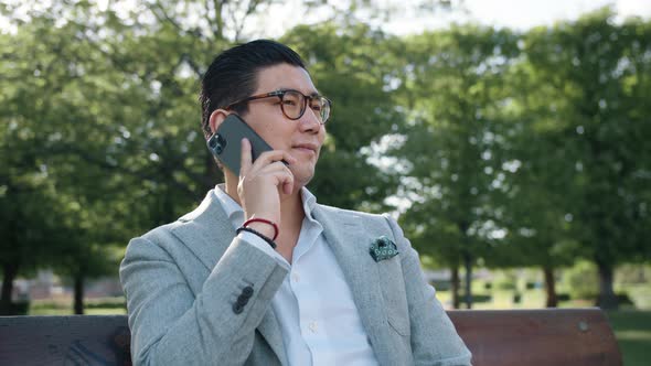 Korean Businessman On Phone In Park