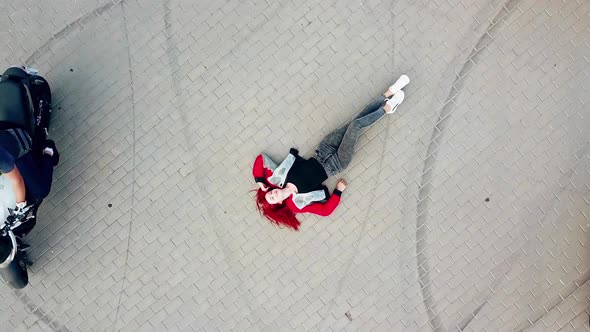 Close-up of an extreme red-haired woman is lying on the road outdoors.