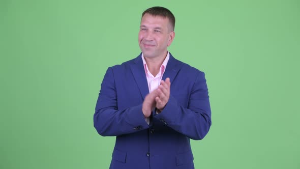 Happy Mature Macho Businessman in Suit Clapping Hands