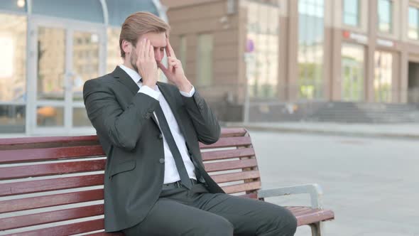 Businessman with Headache Sitting Outdoor on Bench