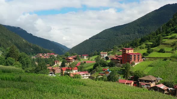 aerial drone flying over a hill revealing a mountain village during a summer morning in Uzungol Trab