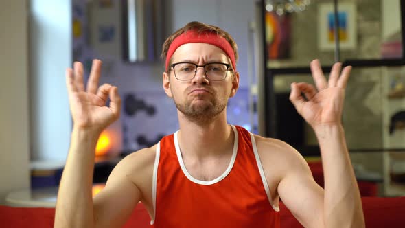 Portrait of funny sportsman in red sportswear making OK sign at home.