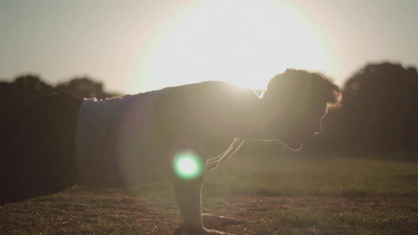 Attractive Young Man Doing Press Ups In The Park During Golden Hour In Slow Motion