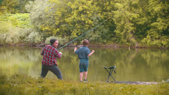 Two Brothers on Fishing - Man Pulling the Rod and His Little Brother Jumping Beside Him