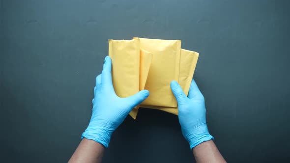 Hand in Latex Gloves Holding White Paper Bubble Envelope for Postal Ship