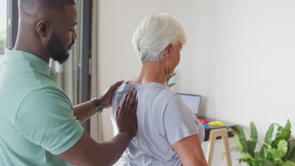 Video of african american male physiotherapist examining caucasian senior woman