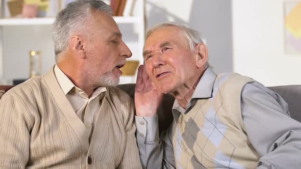 Senior Retired Man With Hearing Problem Listening to Friend, Communication