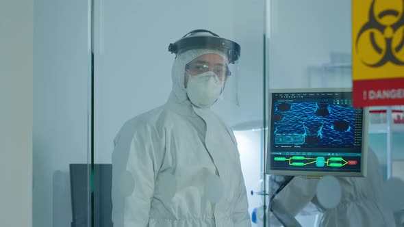 Doctor in Ppe Suit Against Covid19 Looking at Camera Behind the Glass Wall