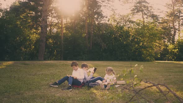 Schoolboys with Little Sister Read Textbooks in Sunny Park