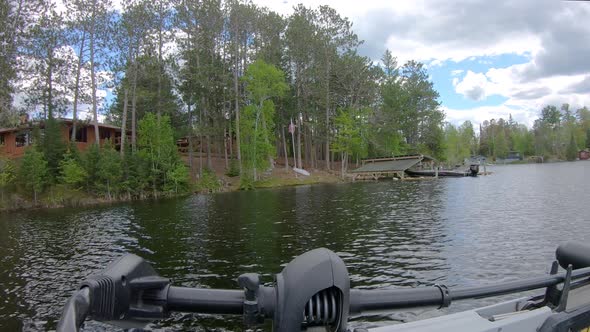 POV - Front of fishing boat and trolling motor while slowly cruising by lake home with flooded dock