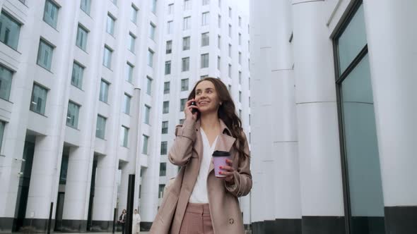 Portrait of a beautiful woman walking along the city street. Business girl close-up smiling