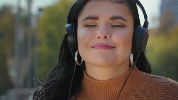 Portrait Young Happy Woman Standing Outdoors in Headphones Listening Favorite Music Using Smartphone