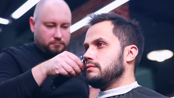 Hispanic Bearded Man Having His Hair Cut By Hairdresser at the Barbershop