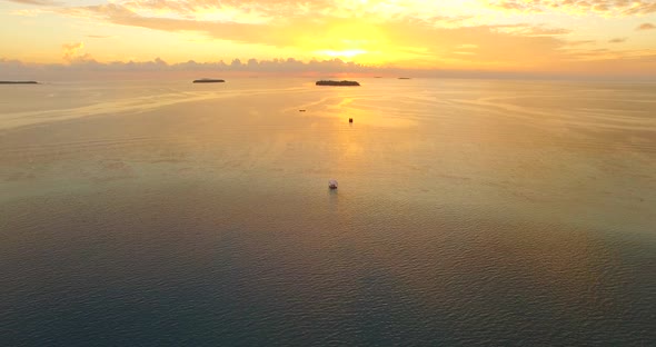 Aerial drone view of a man and woman having dinner on a floating raft boat at sunset.