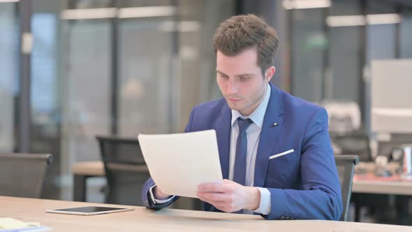Businessman Reading Reports While Sitting in Office