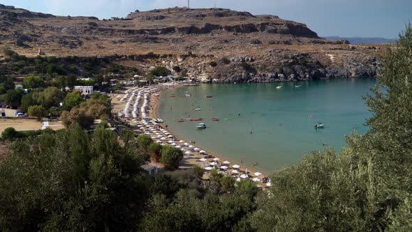 Aerial drone shot of people relaxing on the nautical beach of Lindos