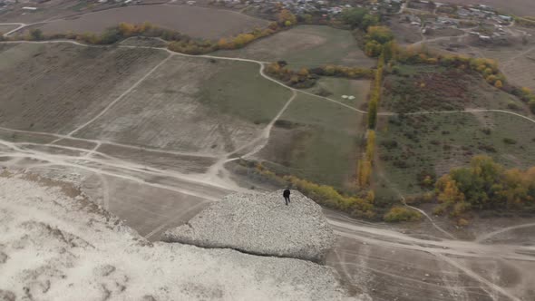 Lonely Man Standing on White Cliff Edge on Field Background Down Below