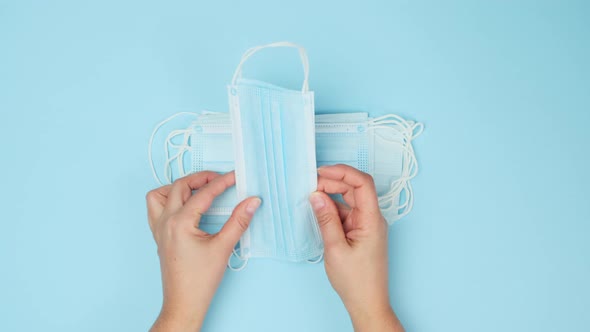 Two female hands hold a stack of disposable face masks