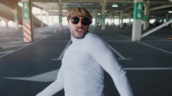 Cheerful and Happy Young Man with Beard Actively Is Dancing While Walking Down the Street on Urban