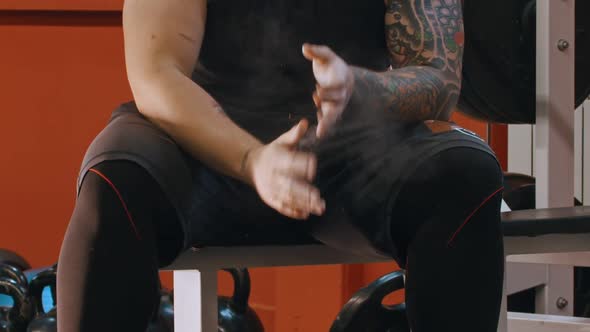 A Muscular Man with a Tattoo Covering His Hands in Talcum and Clapping His Hands