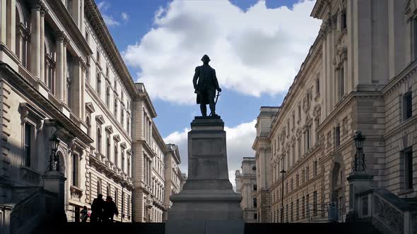 People Walk Up Steps By Classical Buildings And Statue