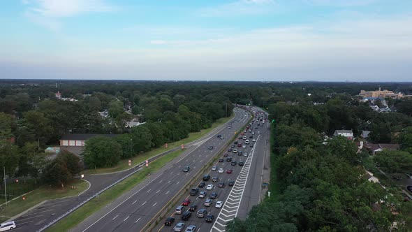 An aerial view next to a busy parkway in the evening during rush hour. The camera dolly in over the