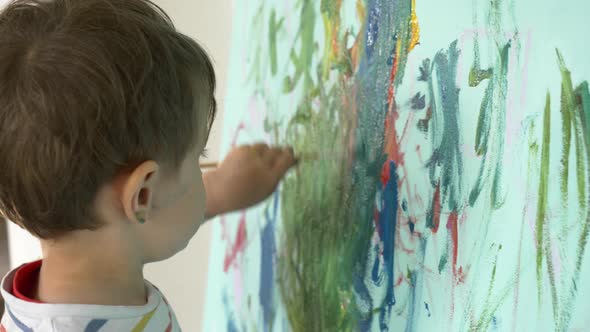 toddler boy is painting on the wall during quarantine