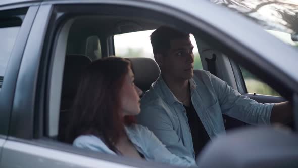 Young Positive Couple Sitting in Car Discussing Trip Route