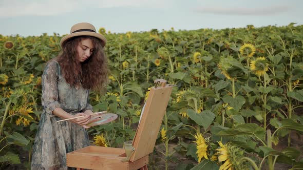Pretty Redhaired Lady Painting with Watercolors Among Sunflowers