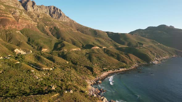 waves crashing on mountain beach in Cape Town at Chapmans Peak during sunset, aerial