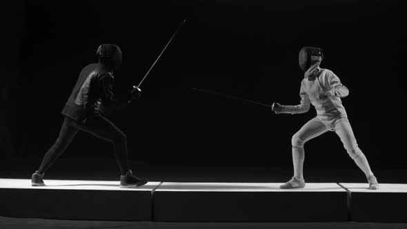 Two Fencing Athletes in Helmets Attacking Each Other