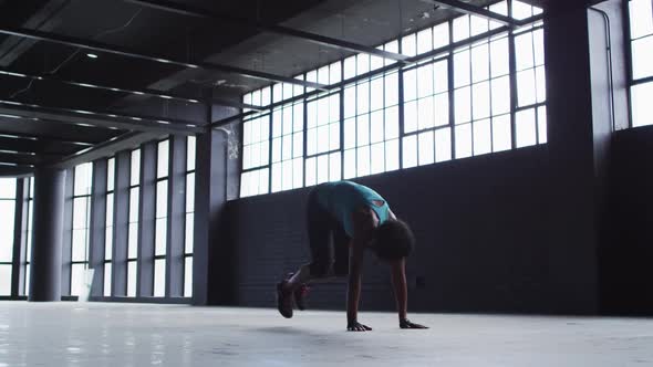 African american woman doing jumping exercises in an empty urban building