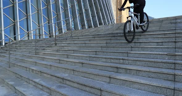 Woman free rider riding bike going down city stairs