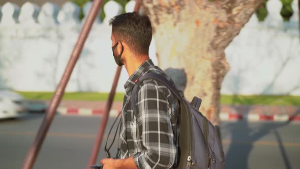 Young man wearing face mask, male tourist walking pedestrian street, epidemic air health illness