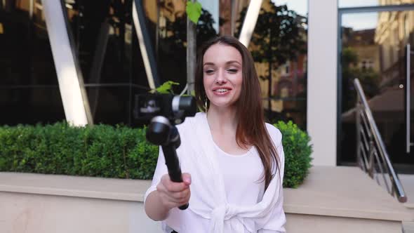 Woman Filming Video On Camera Near Modern Office Building