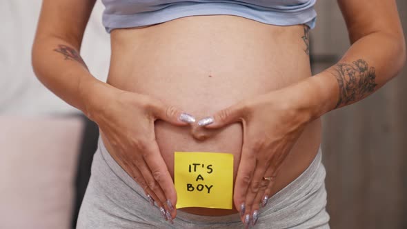 Closeup View of a Pregnant Woman's Belly with a Sticky Note Saying It is a Boy